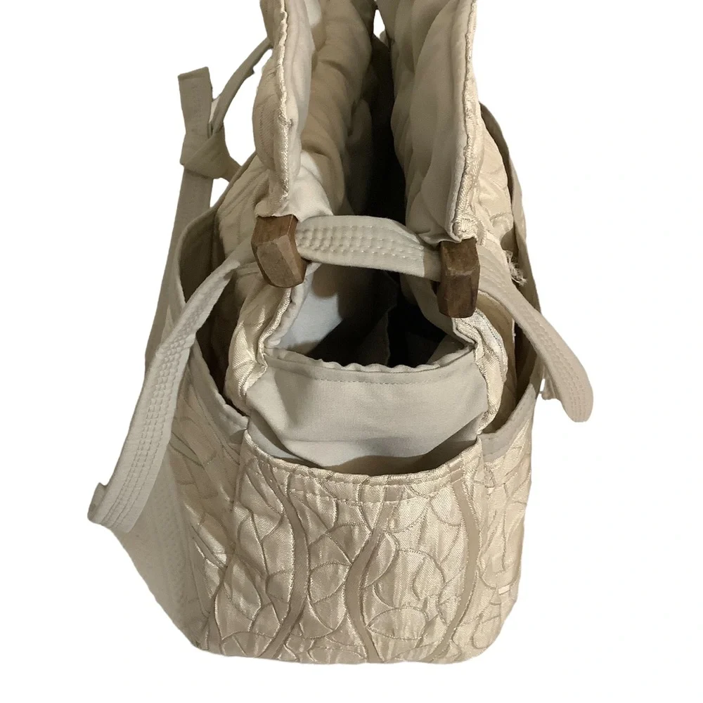 FABRIC SHOULDER BAG WITH OUTSIDE SURROUNDING POCKETS IN A CREAM AND TAUPE COLOR.